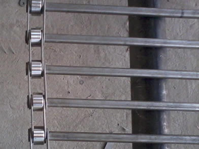 A rod conveyor belt on the shelf with chain link edge.