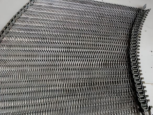 A curved balanced weave conveyor belt on the ground.