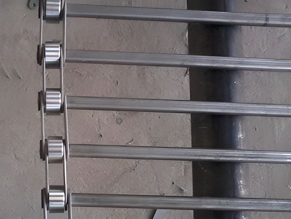 A rod conveyor belt on the shelf with chain link edge.