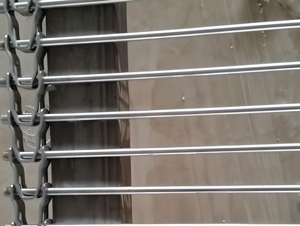 A rod conveyor belt is placed on the shelf with U-shaped link edge.