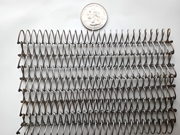 A piece of balanced weave metal conveyor belt with welded edge is beside a metal coin.